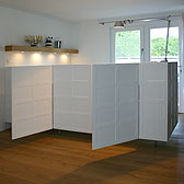 küche mira Planung: Tischlerei Kerber  _ Küchenblock und Sideboard mit weiss lackierten Kassetten _ Arbeitsplatte Edelstahl mit eingeschweißtem Becken und flächenbündigem Kochfeld _ Boden Eiche Massivdiele